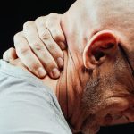 男子手扶颈肩部疼痛部位，表现肌筋膜炎典型疼痛